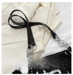 Detail of black and white checkered tweed bag with leather strap and silver metal chain