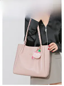 Sac fourre-tout rose gaufré avec poignées tressées et breloque porté par mannequin