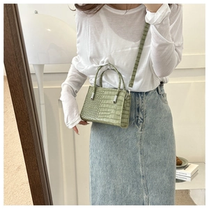 Model showing a mini light green faux crocodile leather tote bag with shoulder strap