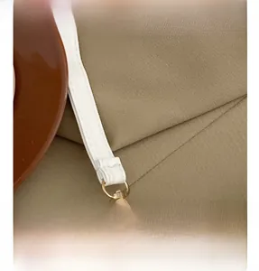 Detail of white leather shoulder strap with gold metal hook on textured fabric background