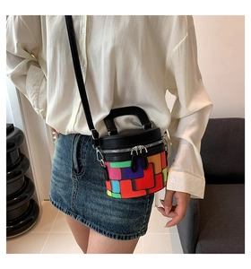 Side view of model wearing a colorful geometric print cylinder bag with silver hardware