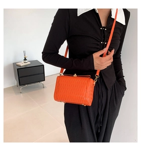 Détail du sac bandoulière orange plissé avec fermoir doré et fine bandoulière en cuir souple