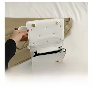 Interior view of the white quilted crossbody bag showing compartments and golden magnetic clasp