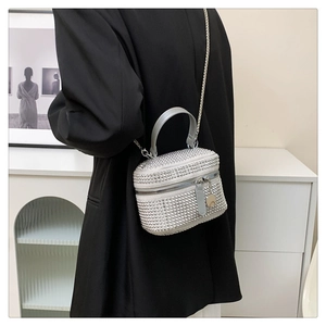 Detailed view of a silver rhinestone mini box bag with chain strap worn by a person