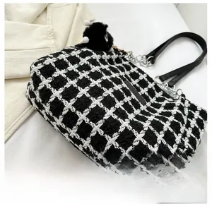 Detailed view of black and white tweed tote bag with leather straps and plush charm