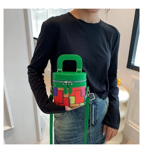 Close-up of colorful checkered cylinder bucket bag with green leather strap on model