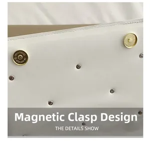 Detail of silver rivets and golden magnetic closures on a white leather shoulder bag