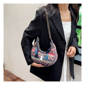 Détail du sac selle tissé bohème avec motifs géométriques colorés et pompons à franges bleues