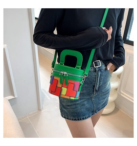 Detail view of colorful geometric pattern and silver double zippers on mini cylinder bag