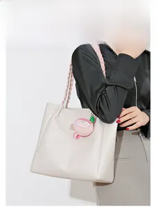 Détail du sac fourre-tout ivoire avec poignées tressées roses et breloque en peluche