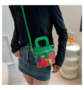 Detailed side view of a colorful plaid cylinder bucket bag worn cross-body by a model