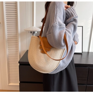 Detailed texture of the beige woven bucket bag with brown leather strap and closure
