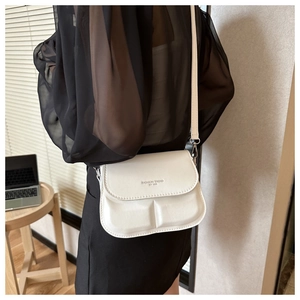 Detail van de witte crossbodytas met reliëf en Fashion-tekst getoond op model