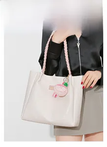 Détail du sac cabas gaufré pied-de-poule avec poignées tissées roses et pendentif mignon