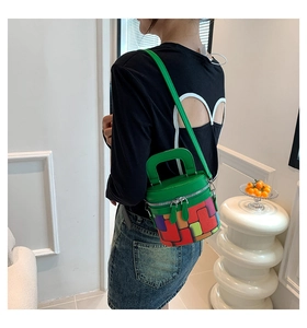 Detail of colorful geometric cylinder bag worn by a model in a sleek black backless top