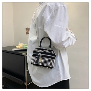 Detail of black cylinder bag featuring silver studs and delicate metal chain strap