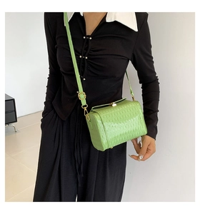 Détail d'un sac cylindre vert vif avec texture plissée et fermoir en métal doré