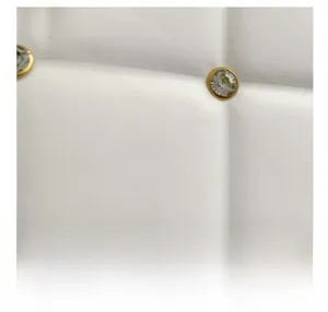 Detailed macro view of white quilted fabric with gold-rimmed crystal stud embellishments