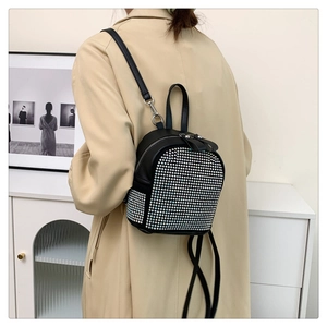Fashionable mini backpack with colorful rhinestones on black leather, worn by a model