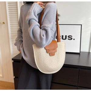 Detail of woven u-shaped tote bag featuring premium brown leather flap and shoulder strap