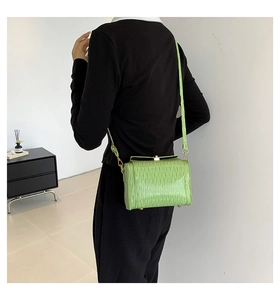 Dettaglio borsa a tracolla verde chiaro con texture a pieghe e chiusura dorata