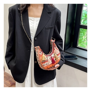 Détails d'un sac bohème tissé avec motifs colorés et pompons sur chaîne dorée