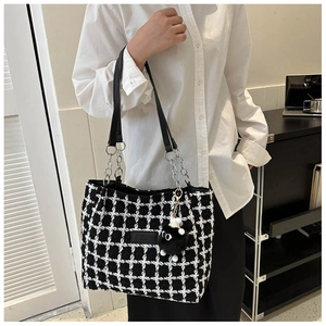 Detail of checkered tweed tote bag with leather chain strap and plush ball accessory
