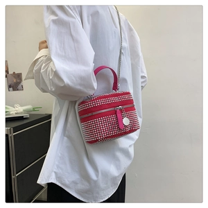 Detail of rose red box bag with silver studs and chain strap shown on a model