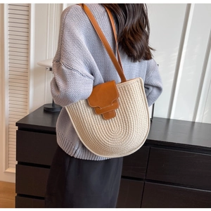 Close-up of a woven cream shoulder bag with brown leather strap and textured rope design