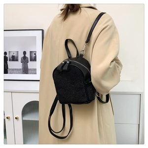 Detail of a sparkling black rhinestone mini backpack worn with a stylish trench coat