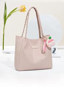 Gros plan du sac cabas en similicuir rose avec anses tressées et pendentif de poupée