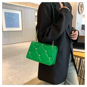 Detail of bright green quilted square bag featuring gold studs and leather shoulder strap