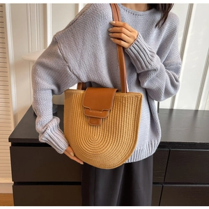 Detail of woven bucket bag with brown leather flap and white stitching craftsmanship