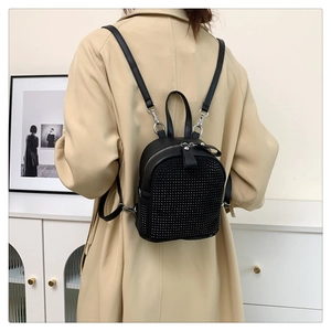 Close-up of black mini backpack with sparkling rhinestones worn by a model in a trench coat