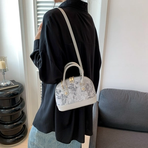Sac à main vintage avec broderie grise et détails dorés porté par un mannequin