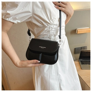 Detail van zwarte PU-lederen crossbodytas met witte tekst op een model in witte jurk