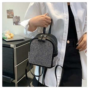 Détail d'un mini sac à dos en similicuir noir orné de clous argentés et d'un zip en métal