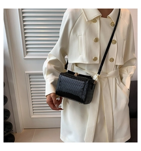 Détail du sac cylindre noir à motif crocodile avec fermoir doré et bandoulière en cuir