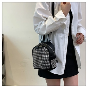 Detail of a black mini backpack with silver rivets and studs on a side-profile model