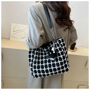 Detail of black and white tweed bucket bag with leather strap and plush charm