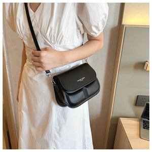Detail of black crossbody bag with white FASHION TREND text on casual white dress