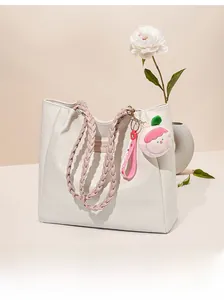 Gros plan du sac cabas blanc en cuir texturé avec anses roses et bijou de sac