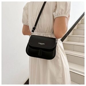Detailed view of black flap crossbody bag with white typography and vertical textures