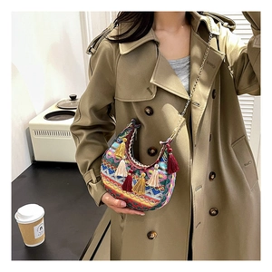 Détails de broderie bohème et pompons colorés sur un sac besace à chaîne en gros plan