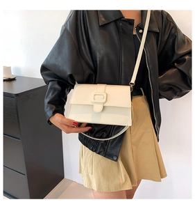 Detail of cream white leather crossbody bag with square buckle on a black leather jacket