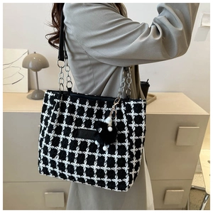 Detail of black and white houndstooth tweed tote bag with silver chain strap and plush charm