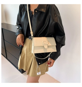 Detail of a minimalist two-tone crossbody bag with a large square buckle and adjustable strap