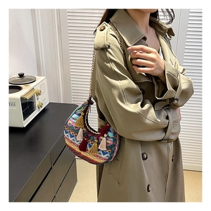 Détails de broderies ethniques colorées et glands en soie sur un sac selle bohème à chaîne
