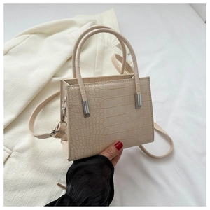 Detail of cream faux leather handbag with crocodile pattern and cylindrical handle