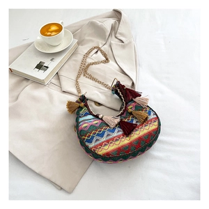 Gros plan d'un sac bohème tissé avec des motifs géométriques et des glands colorés